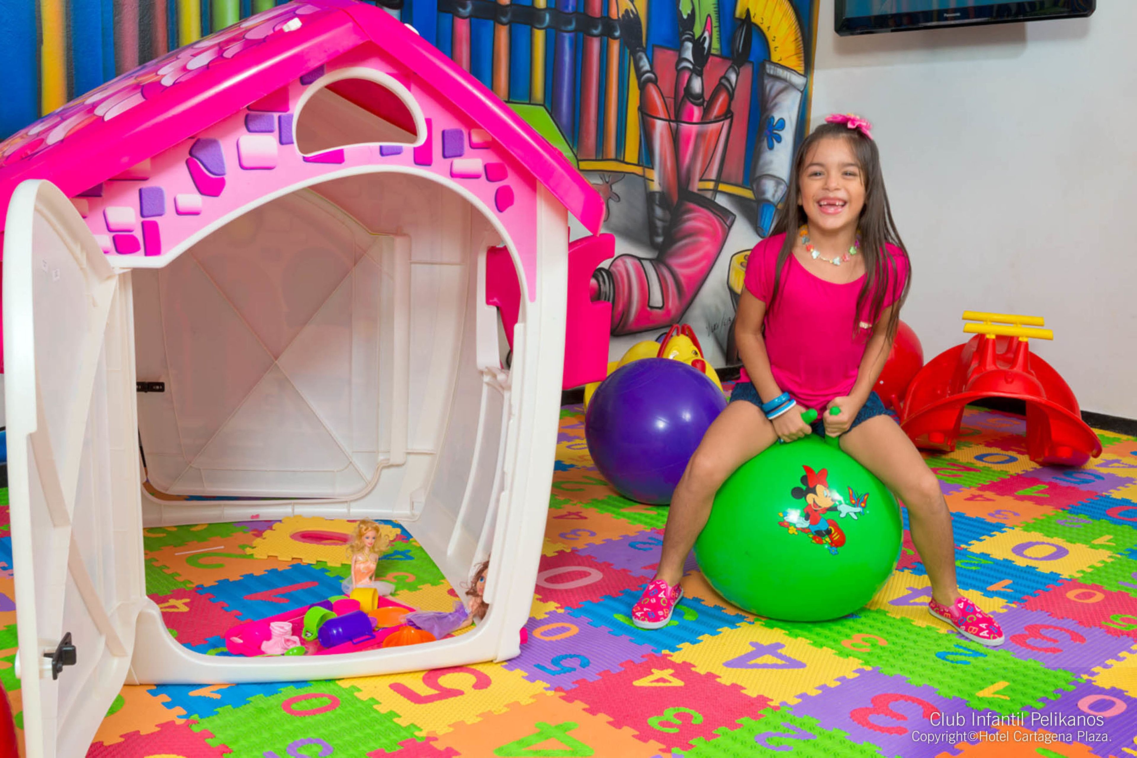 Un niño jugando dentro de una casa de juegos colorida, con piso de colchonetas de espuma.