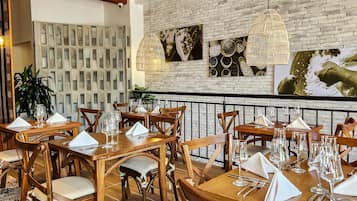 Interior de restaurante con paredes de ladrillo, mesas y sillas de madera.
