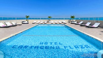 Relax by the pool at Hotel Cartagena Plaza, surrounded by palm trees and lounge chairs.