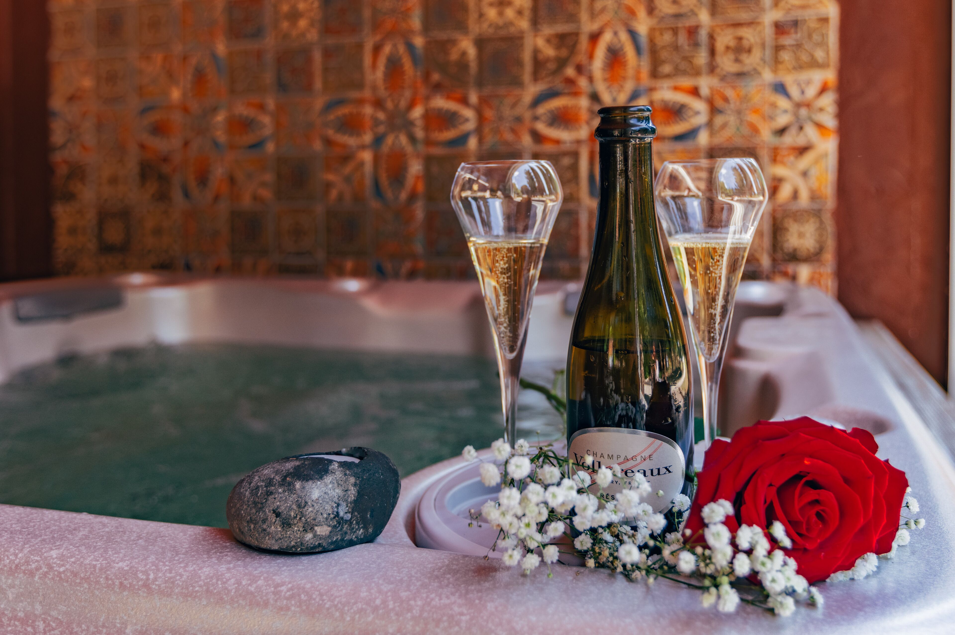 Un jacuzzi con champán y una rosa roja.