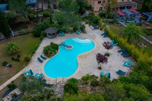Vista aérea de un resort con piscina, sillas de descanso y un pabellón.