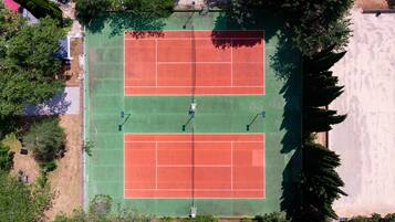 An aerial view of a tennis court with surrounding trees and a building in the background.