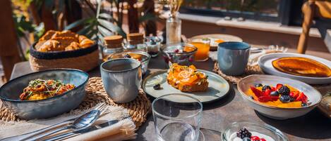 A table set with various dishes, including a bowl of pasta, a plate of salmon, and a bowl of fruit salad.