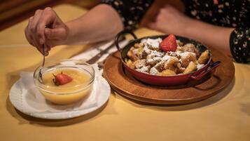 A dessert plate with a bowl of custard and a serving of bread pudding topped with strawberries and powdered sugar.