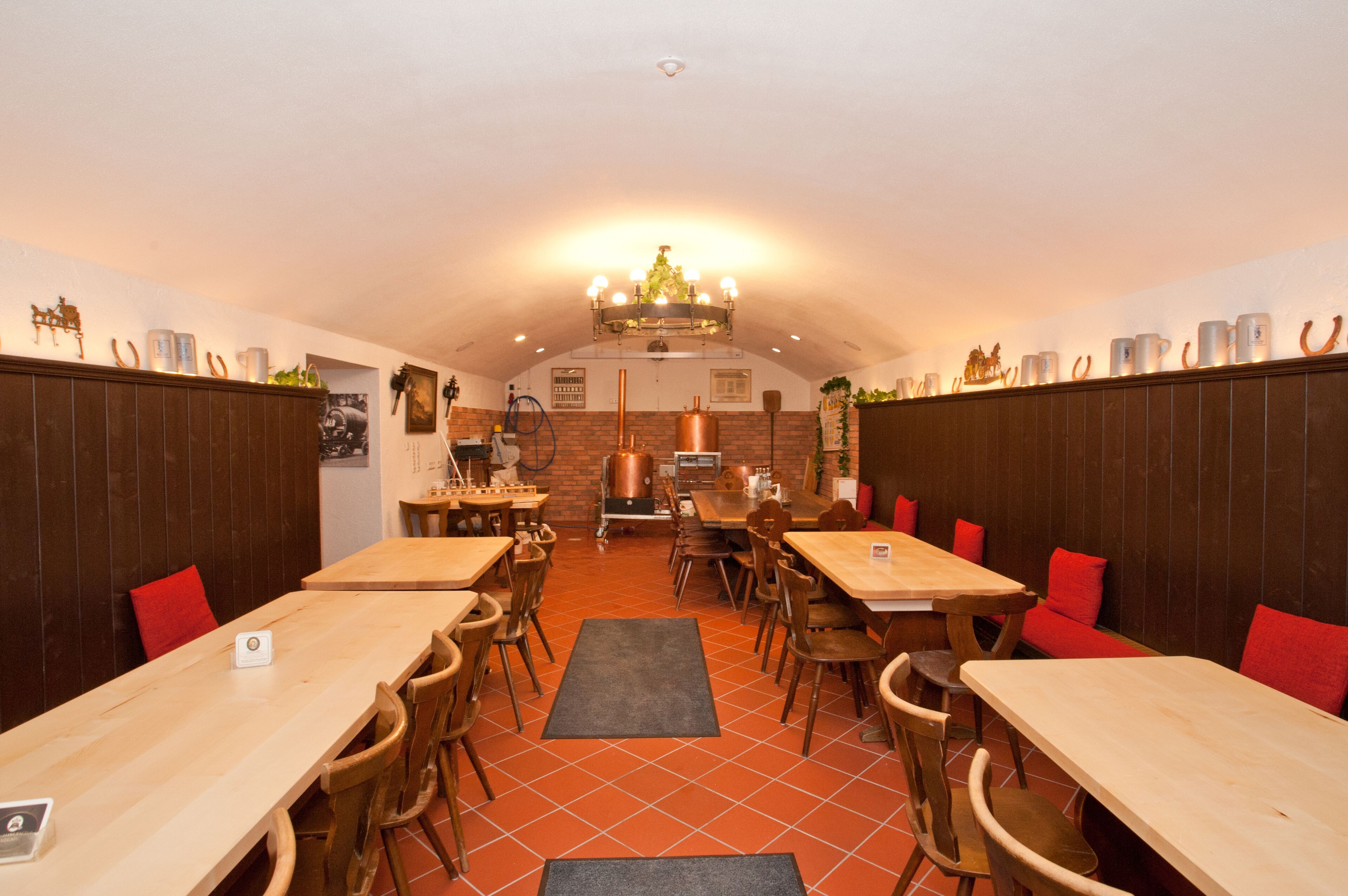 Ein Restaurant mit Holztischen und -stühlen, einem Fliesenboden und einer Ziegelwand.