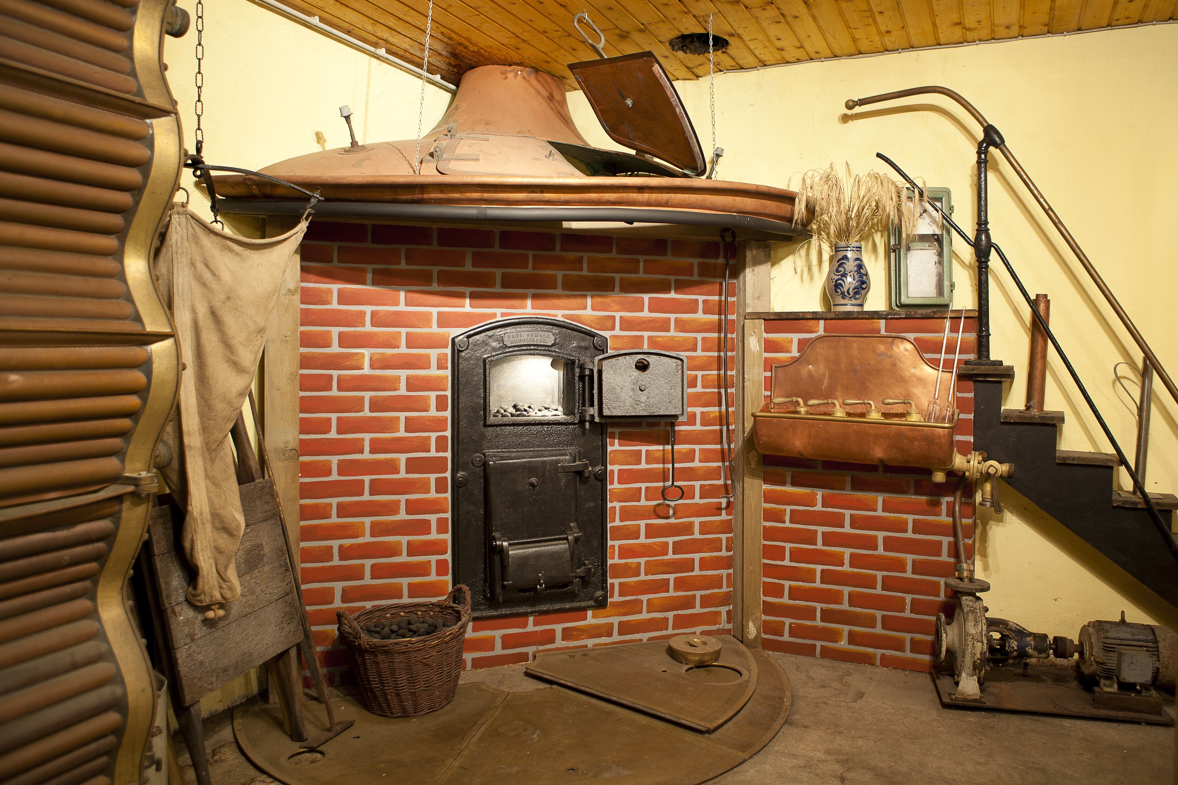 A brick oven with a chimney, a wooden bench, and a basket of firewood.