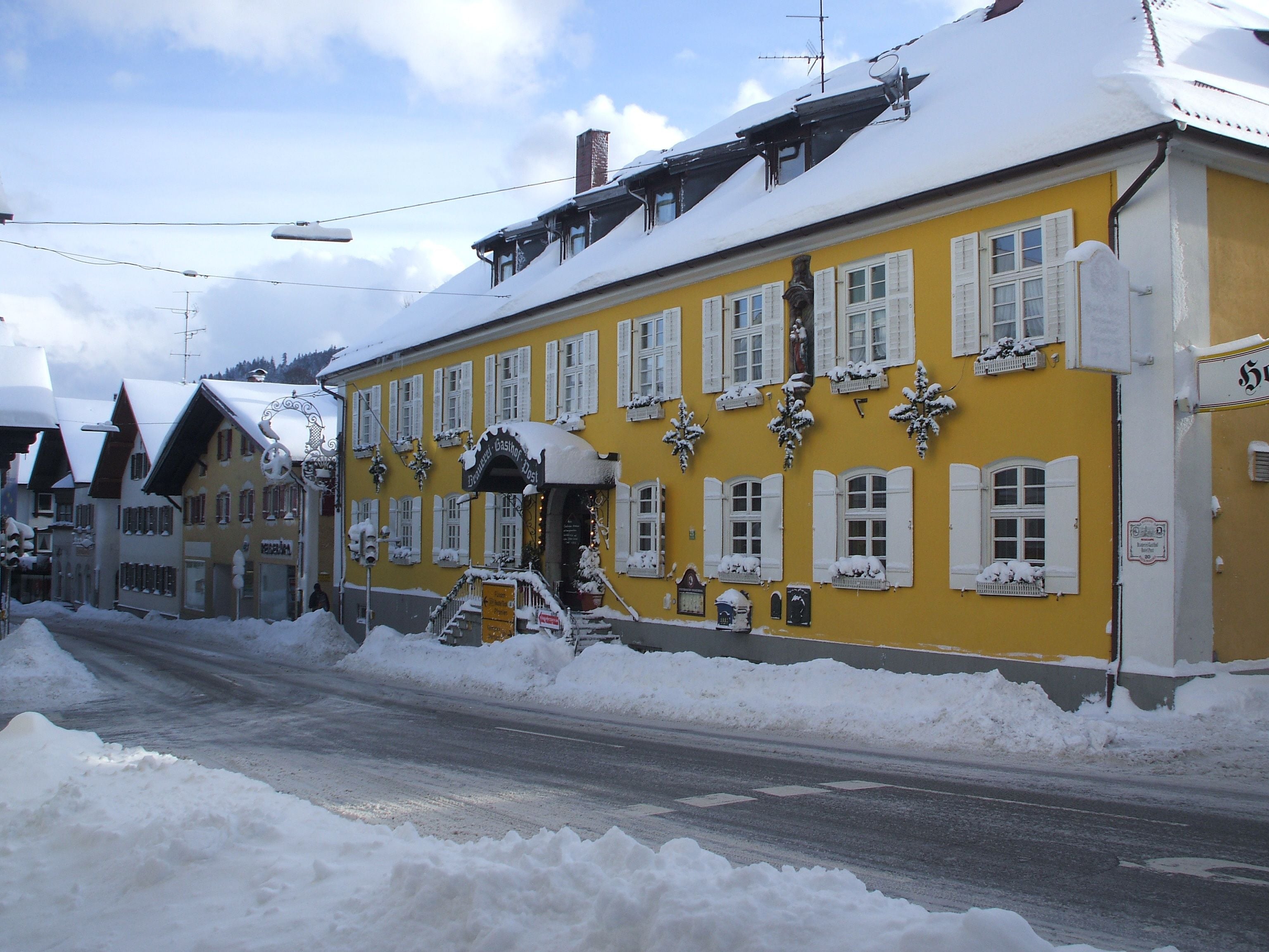 Ein gelbes Gebäude mit schneebedeckten Fenstern und einem Schild, das es als Hotel kennzeichnet.