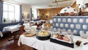 Un espace repas avec des tables préparées pour le petit-déjeuner, proposant une variété d’aliments et un buffet.