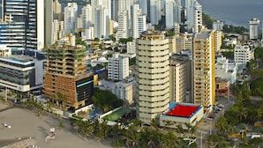 A coastal cityscape with high-rise buildings, a sandy beach, and umbrellas. - Hotel Dorado Plaza Bocagrande - All Inclusive (Cartagena)