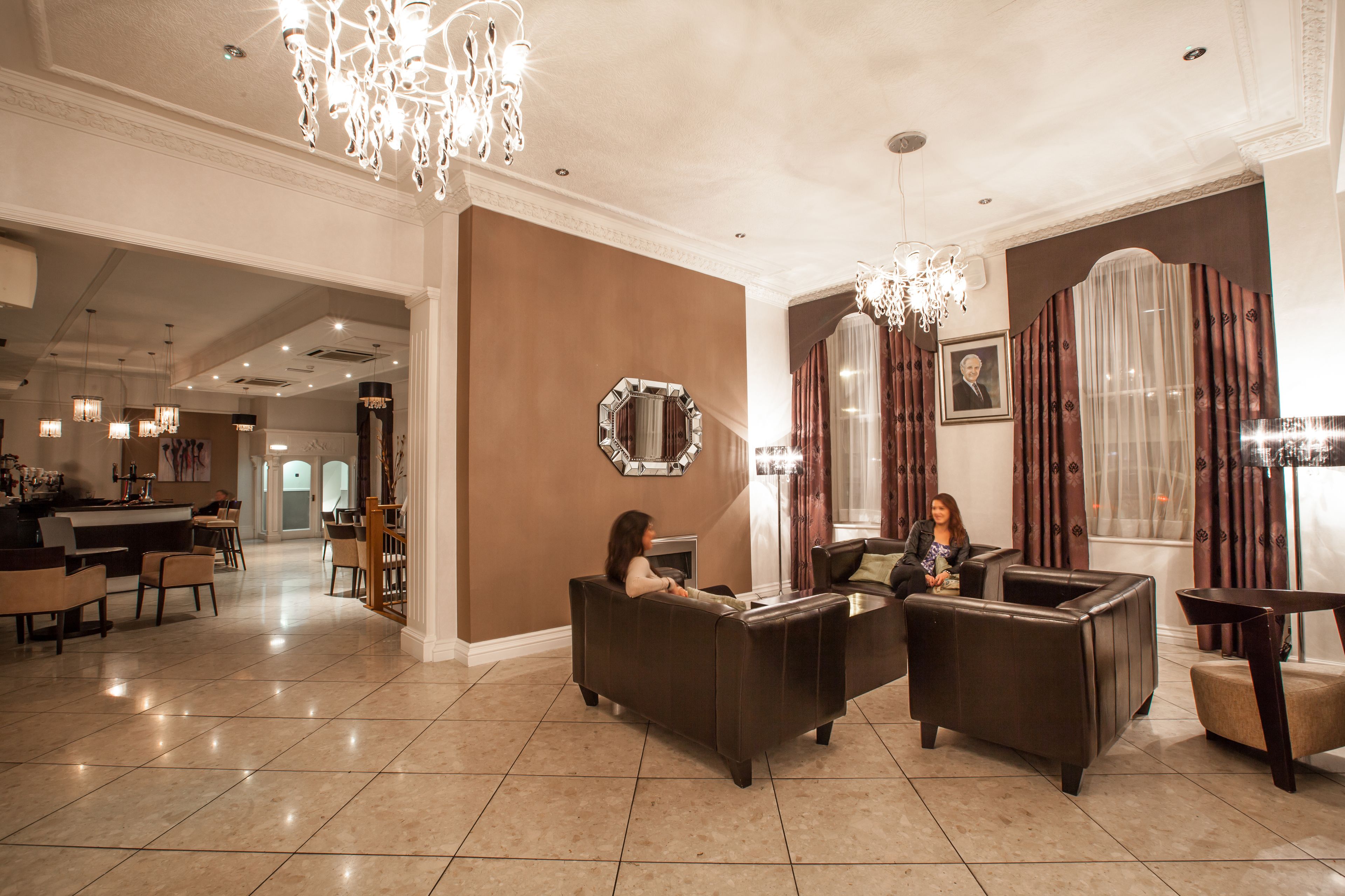 A spacious lobby with a bar area, leather sofas, and a chandelier.