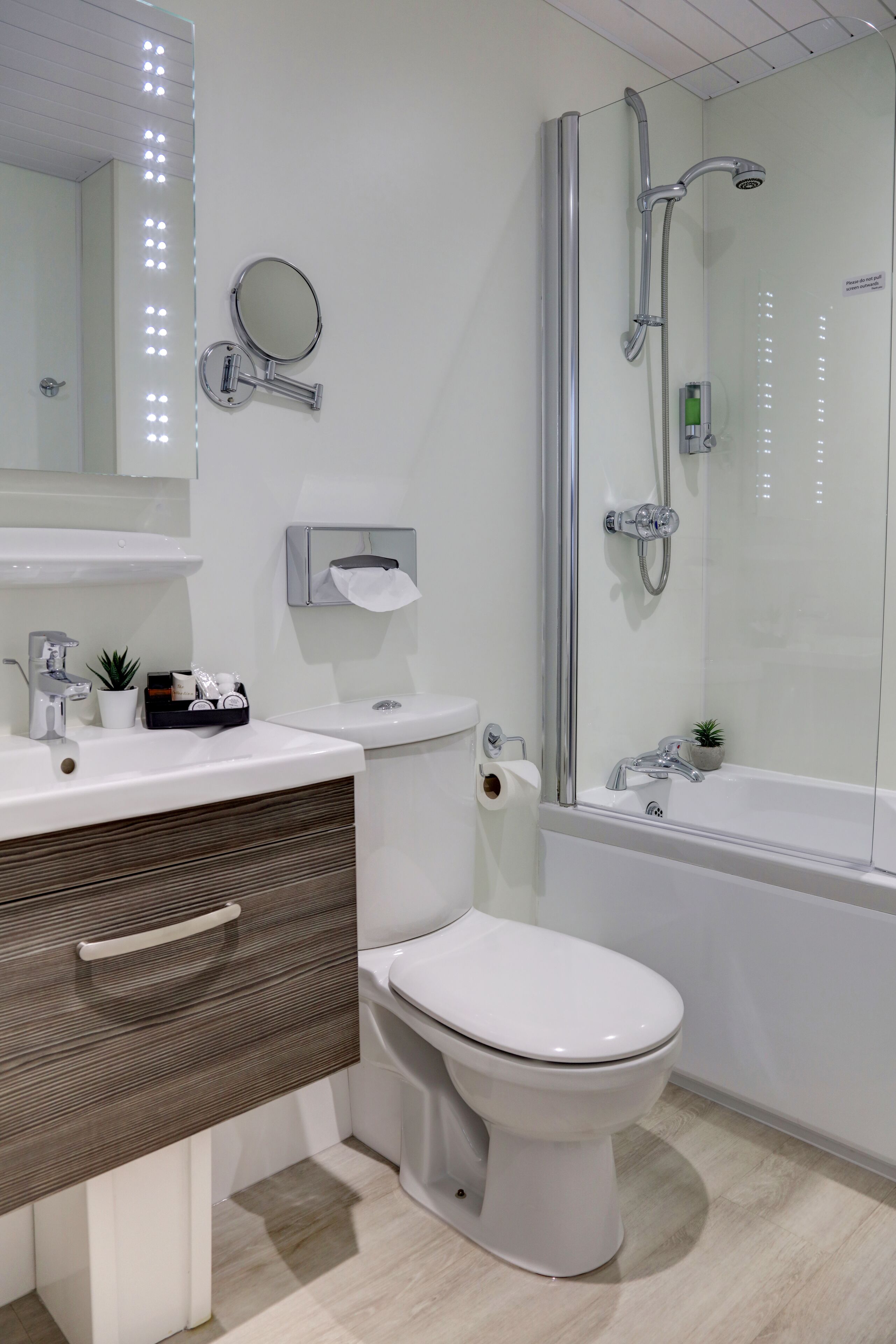 A modern bathroom with a white sink, mirror, toilet, and glass-enclosed shower.