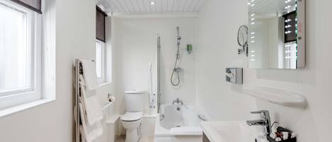 A modern bathroom with a toilet, bathtub, and sink.