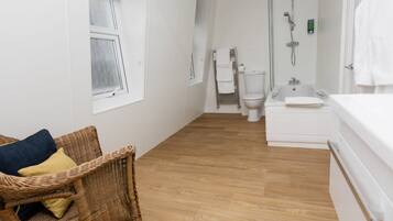A modern bathroom with a white toilet, a bathtub, and a shower.