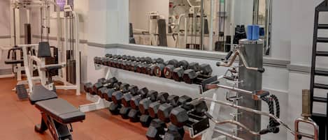 A gym with various exercise equipment, including dumbbells, benches, and weight machines.