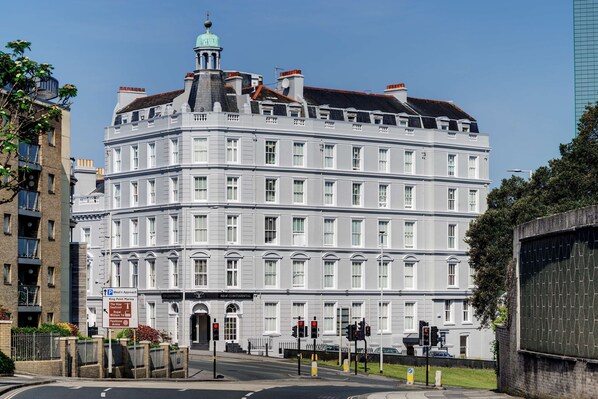 A large, multi-story building with a classic architectural style, featuring a prominent tower with a green dome.