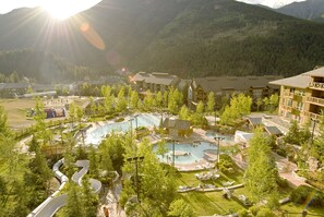 A resort with multiple swimming pools, a water park, and a mountainous backdrop.