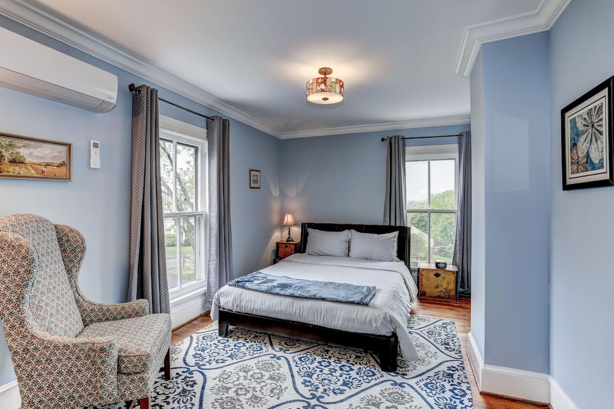 A bedroom with a bed, a chair, a window, and a ceiling light.