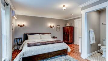 Un dormitorio con una cama grande, un armario de madera y un baño con inodoro y lavabo.