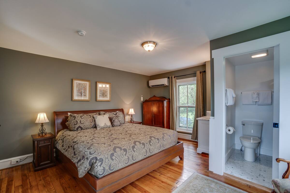 A bedroom with a large bed, bedside lamps, a wardrobe, and a window with curtains.