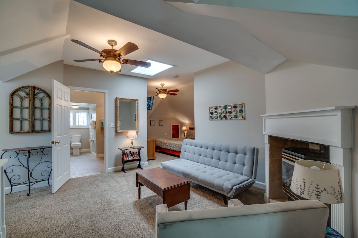 A spacious living room with a sofa, a coffee table, a fireplace, and a ceiling fan.
