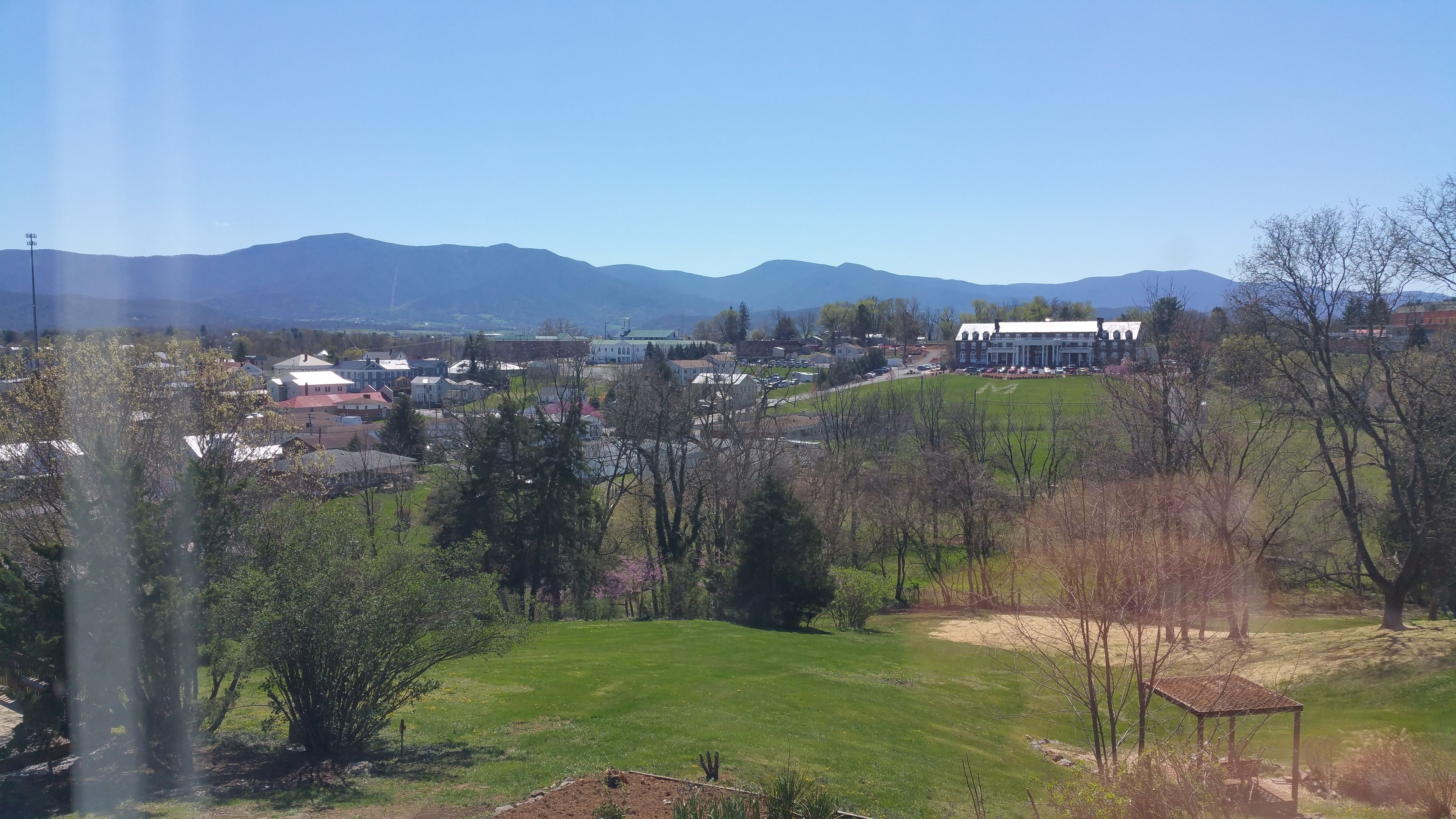 A town with a prominent building with a green roof, surrounded by green fields and trees.
