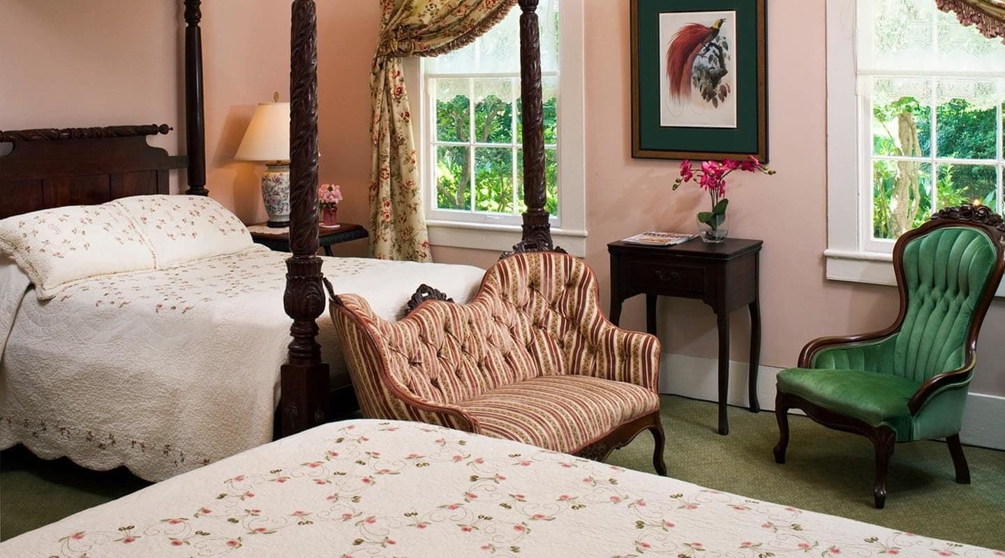 Un dormitorio con cama con dosel, un sillón verde y una silla a rayas.