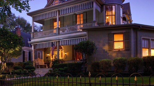 A two-story Victorian-style house with a wrap-around porch, a balcony, and a well-maintained front yard. - Devereaux Shields House (Natchez)