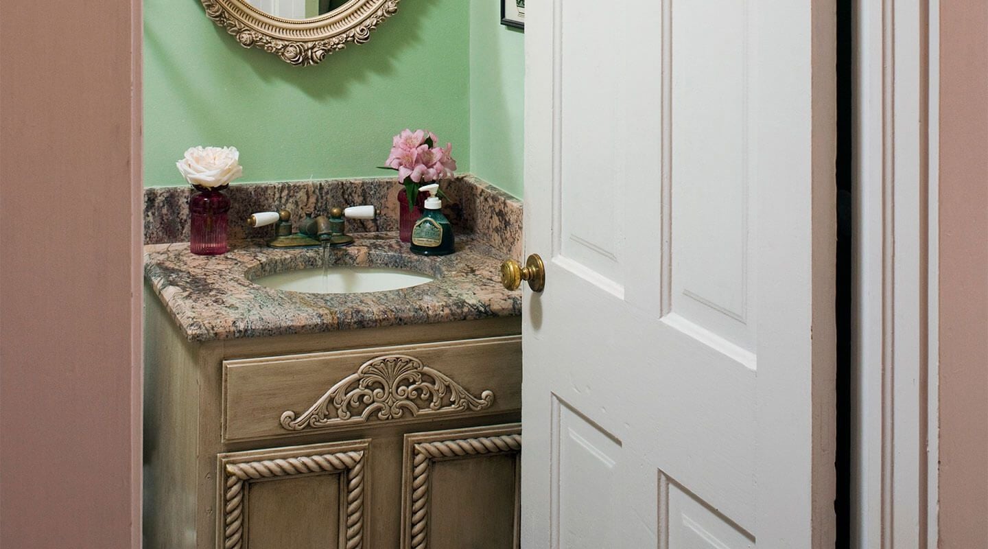 A bathroom with a marble sink, decorative flowers, and a mirror with an ornate frame.