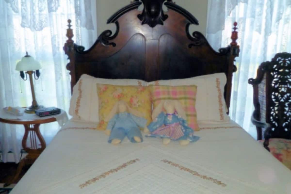 Un dormitorio con una cama grande, una mesita de noche, una lámpara y una silla.