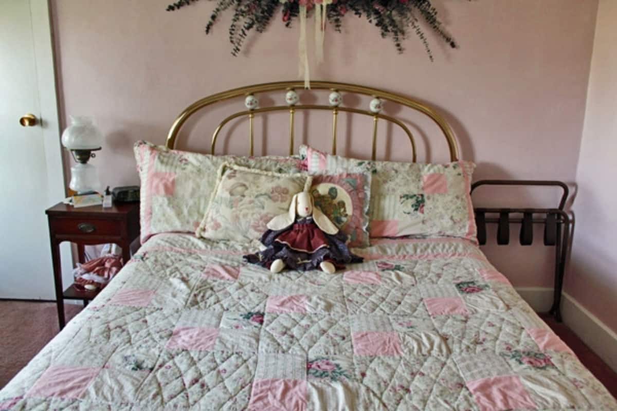 Un dormitorio con una cama, una mesita de noche, una lámpara y un estante en la pared.