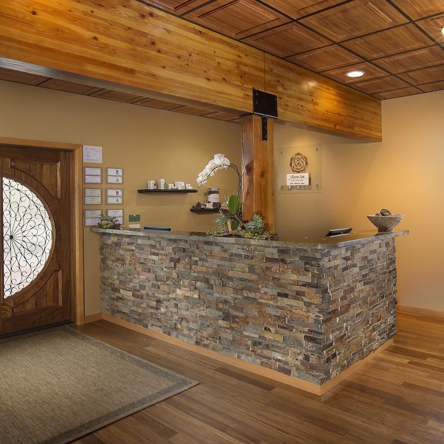 A reception area with a stone counter, wooden doors with glass panels, a small plant, and a sign on the wall.