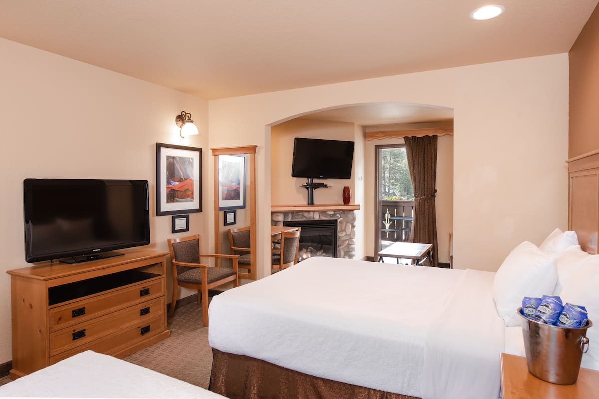 A hotel room with a bed, a TV, a fireplace, and a dining area.