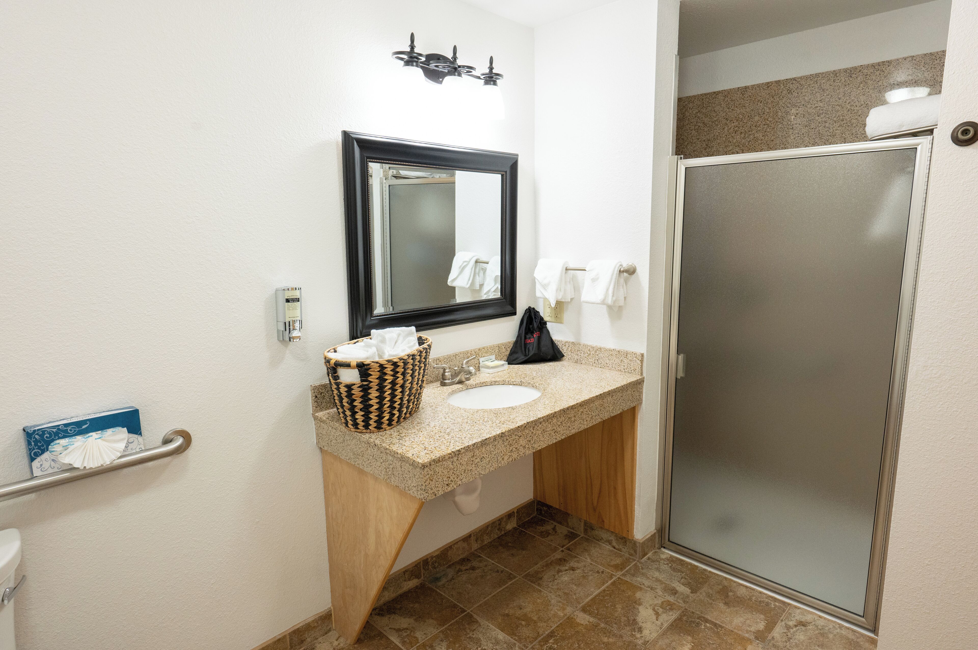 A bathroom with a sink, mirror, towel rack, and a shower stall.