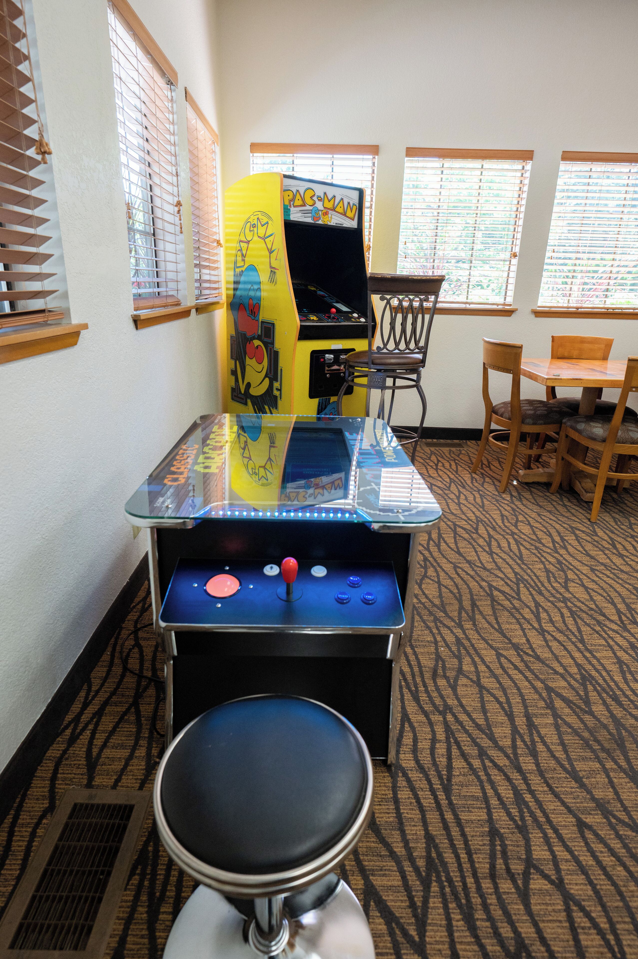 A room with a classic arcade game, a chair, and a table.