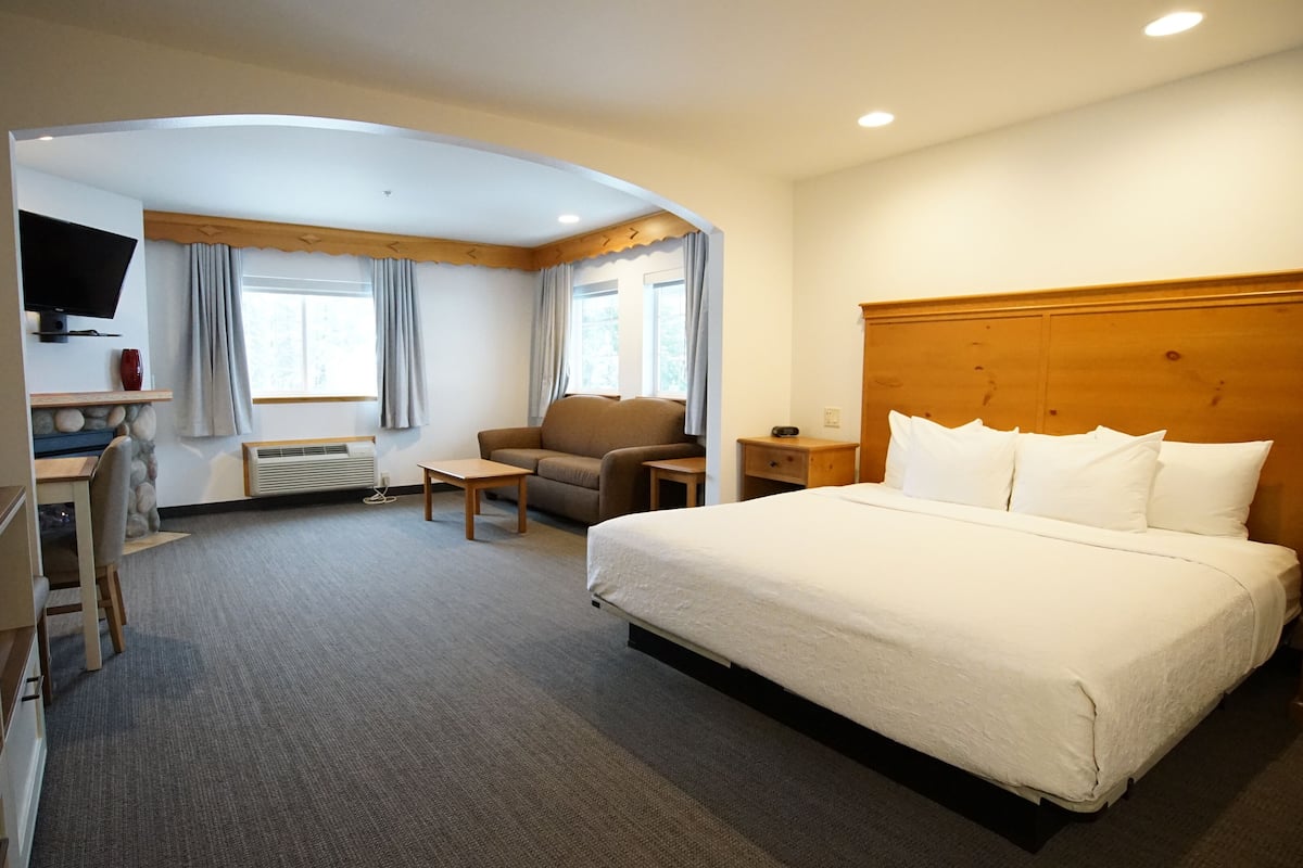 A hotel room with a large bed, a desk, a chair, and a TV.
