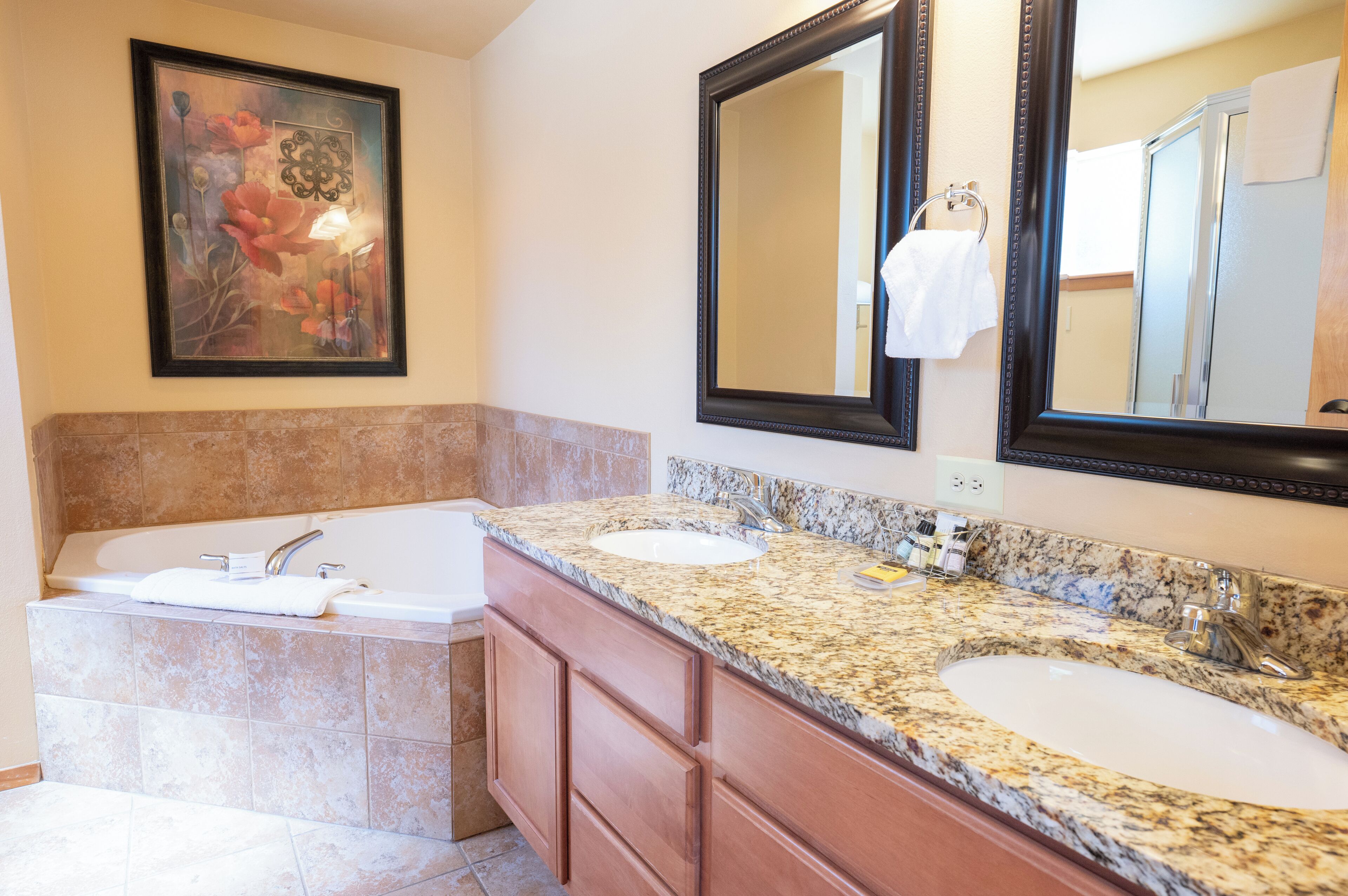 A bathroom with two sinks, a bathtub, and a large mirror.