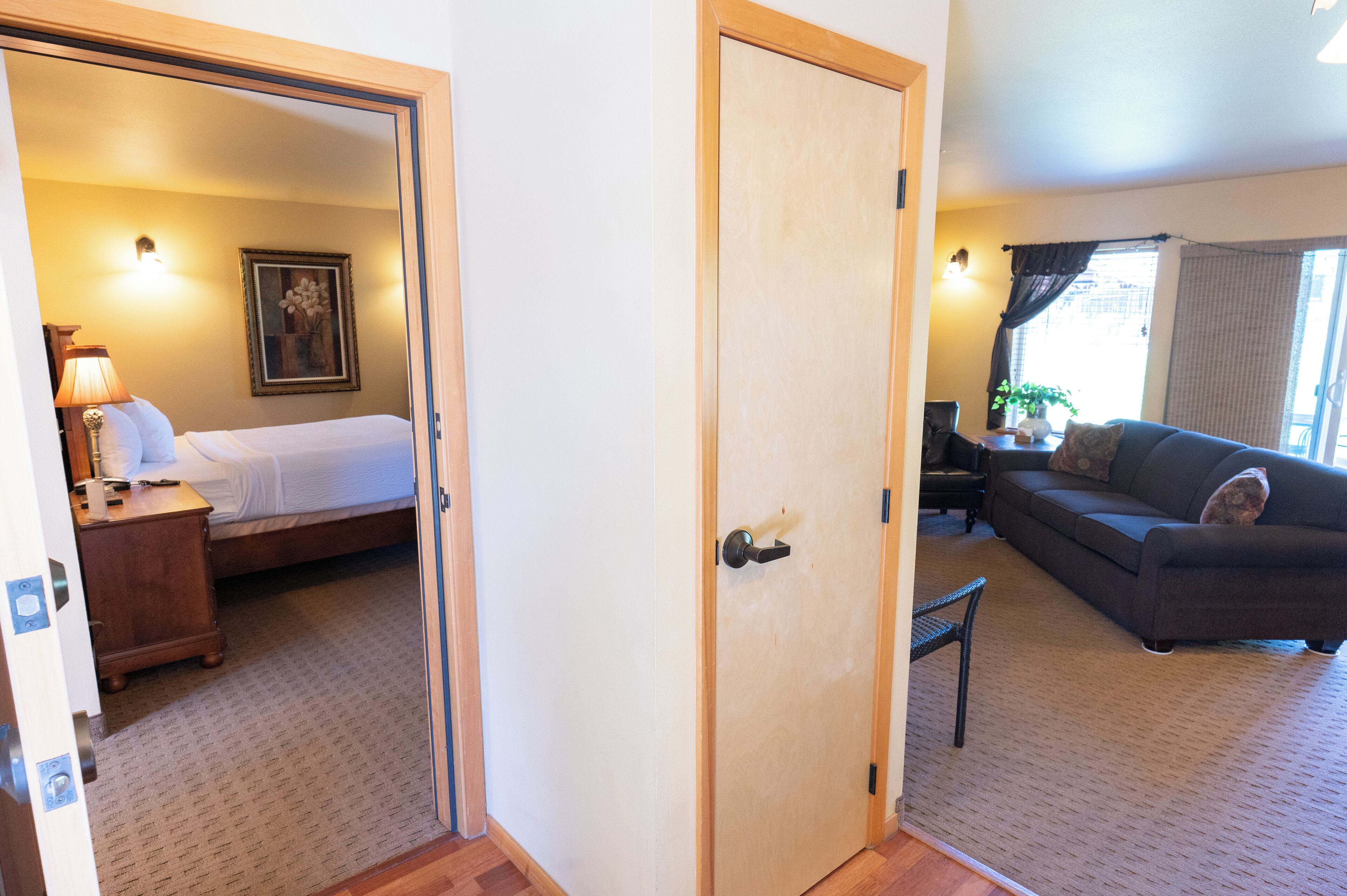 A room with a bed, a sofa, a door, and a lamp.