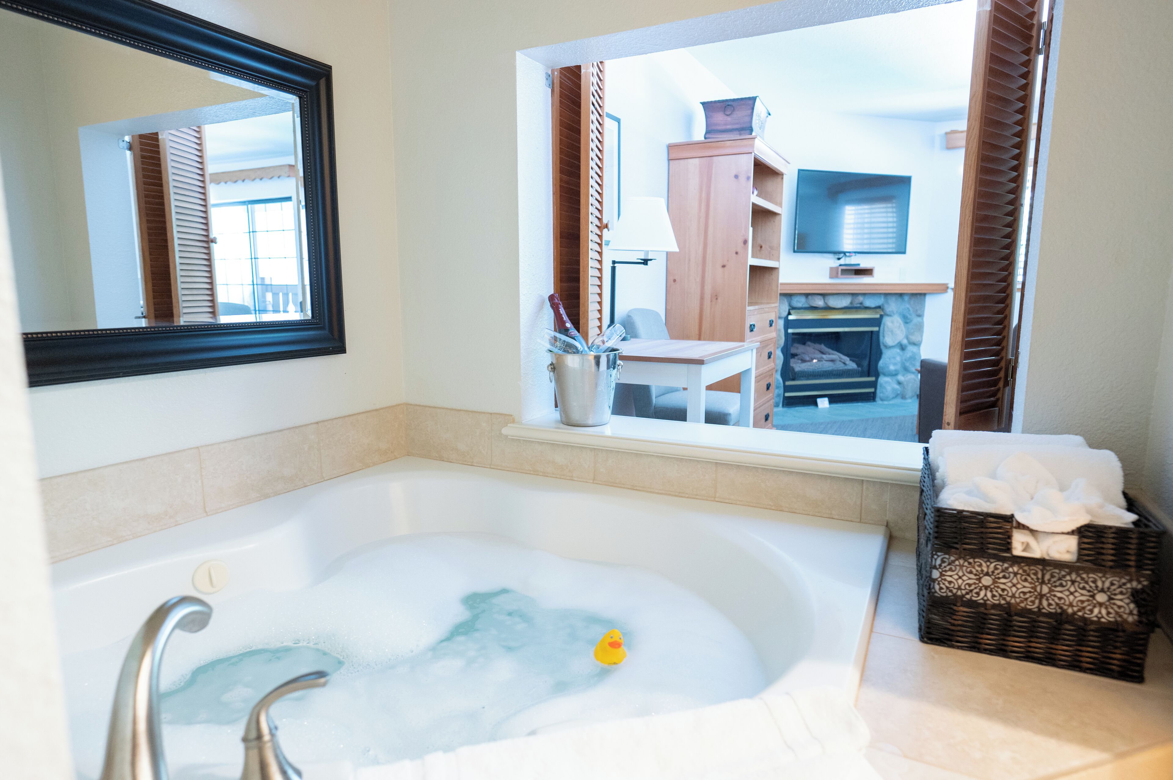Une salle de bain avec une baignoire, un miroir, une fenêtre et un panier en osier.
