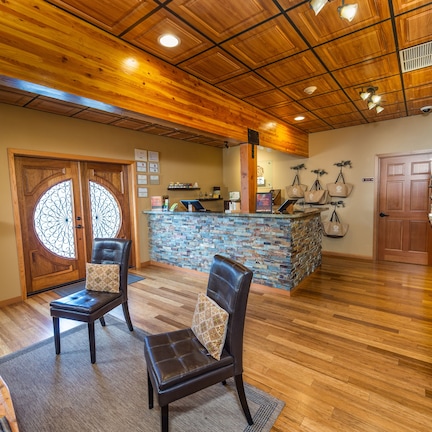 A lobby with wooden flooring, a reception desk, and seating areas.
