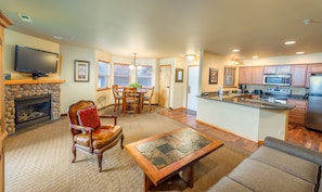 A spacious living room with a fireplace, a dining area, and a kitchen with modern appliances.