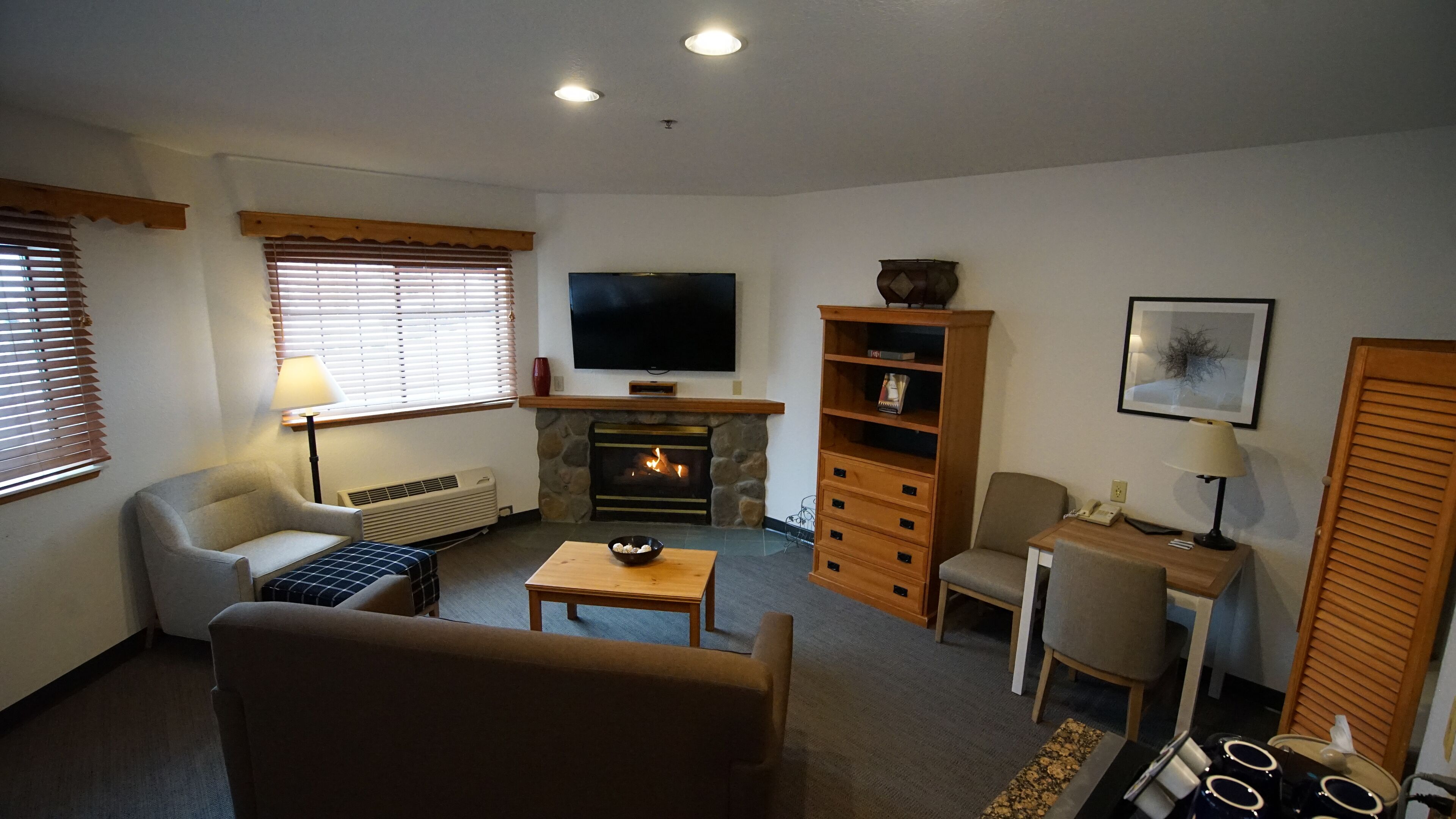 A living room with a fireplace, a television, a sofa, a coffee table, and a bookshelf.