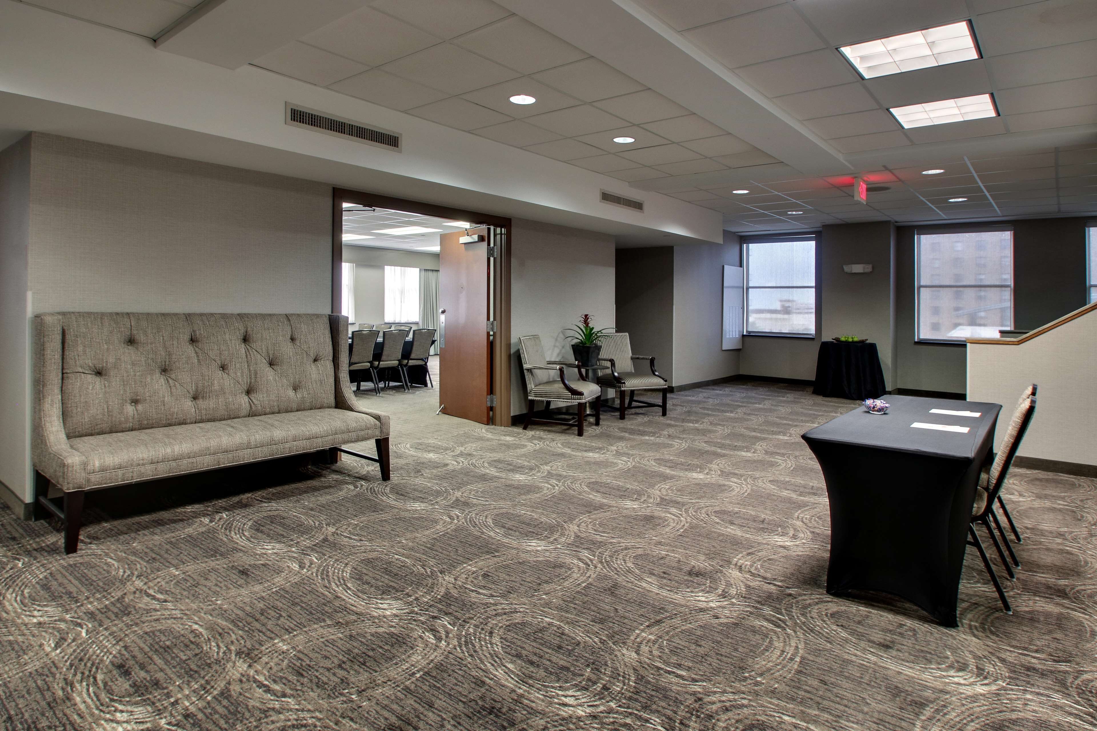 A conference room with a sofa, chairs, a table, and a carpeted floor.