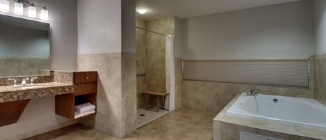 A modern bathroom with a large bathtub, a shower, and a vanity with a mirror and lights.