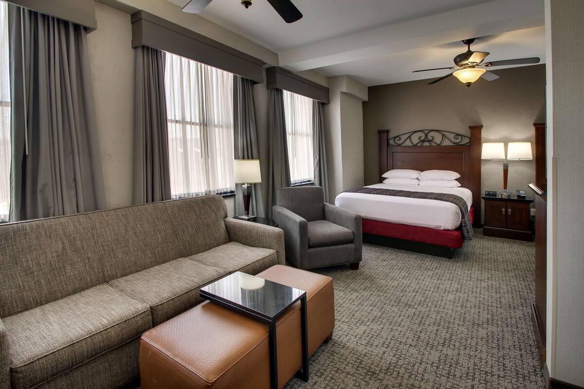 A hotel room with a sofa, armchair, bed, and a small table.