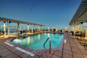 A rooftop pool with clear views of the city, surrounded by outdoor seating and a covered area.