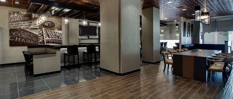 A modern interior with a bar area, seating, and a large screen.