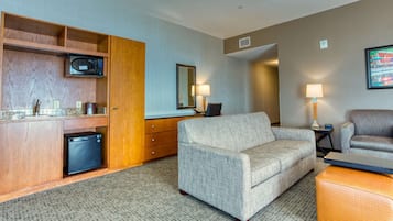 Ein Hotelzimmer mit einer Küchenzeile, einem Sofa, einem Sessel und einem kleinen Tisch.