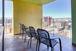 A balcony with four chairs and a table, offering a view of a cityscape with buildings and a red dome structure.