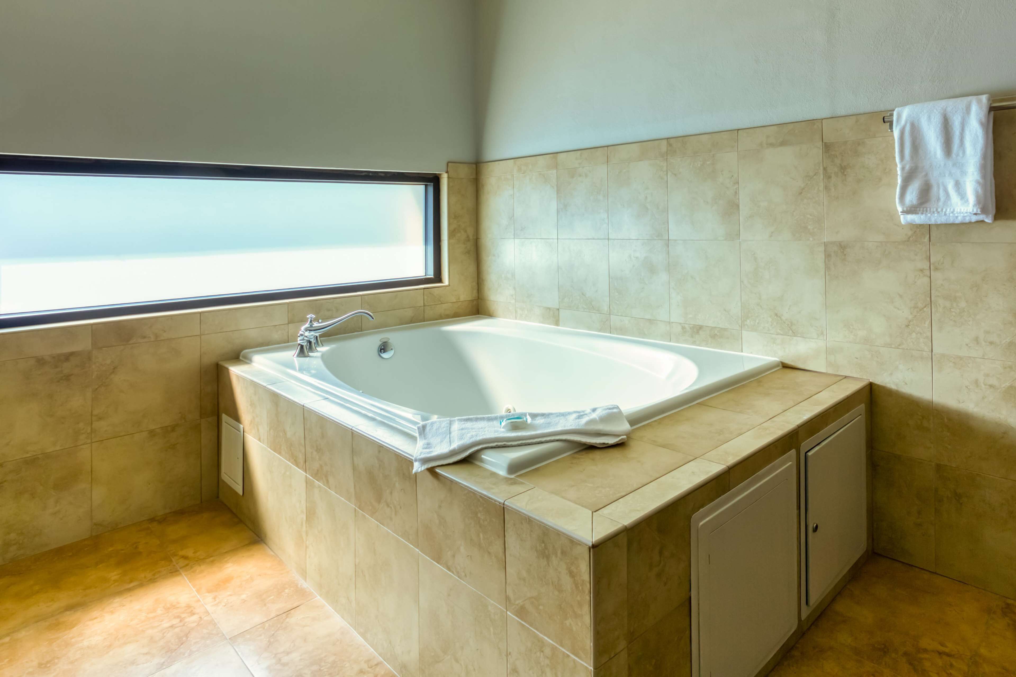 A modern bathroom with a freestanding bathtub, a window, and a towel hanging on the wall.