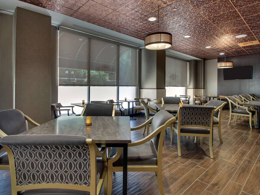A conference room with large tables and chairs, a patterned ceiling, and large windows.